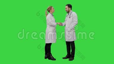 快乐的医生和年轻的护士微笑着，互相<strong>感谢</strong>，在绿色屏幕上握手，Chroma键。